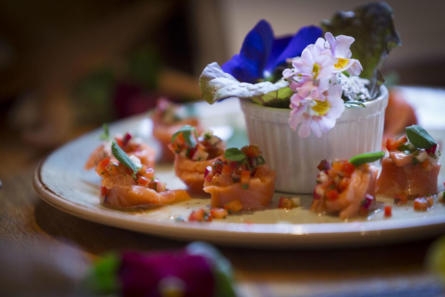 A beautifully presented dish of sockeye salmon with herbs and edible flowers awaits guests at Tutka Bay Lodge, located in an isolated setting accessible only by boat or float plane.