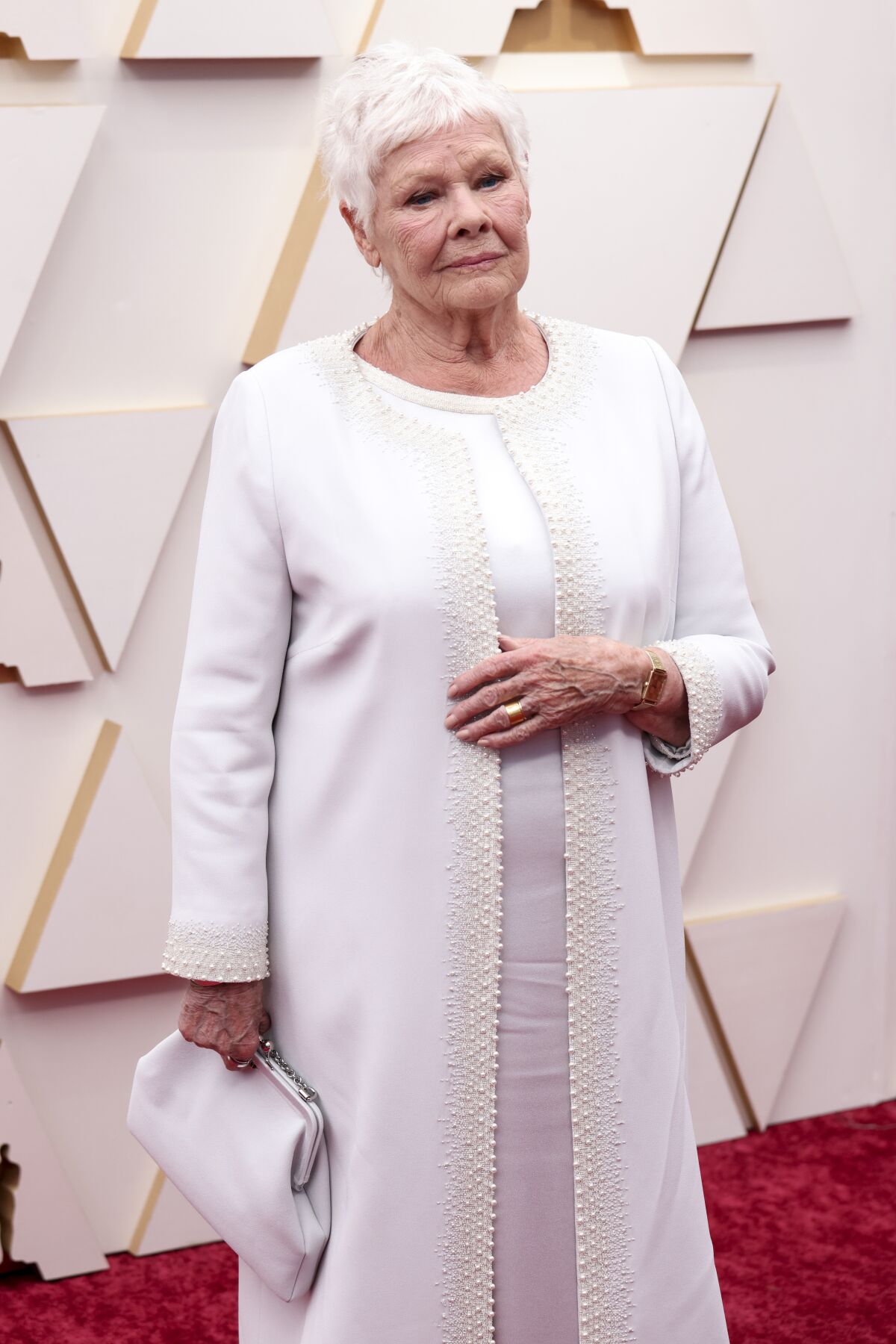 A woman stands on a red carpet dressed in white