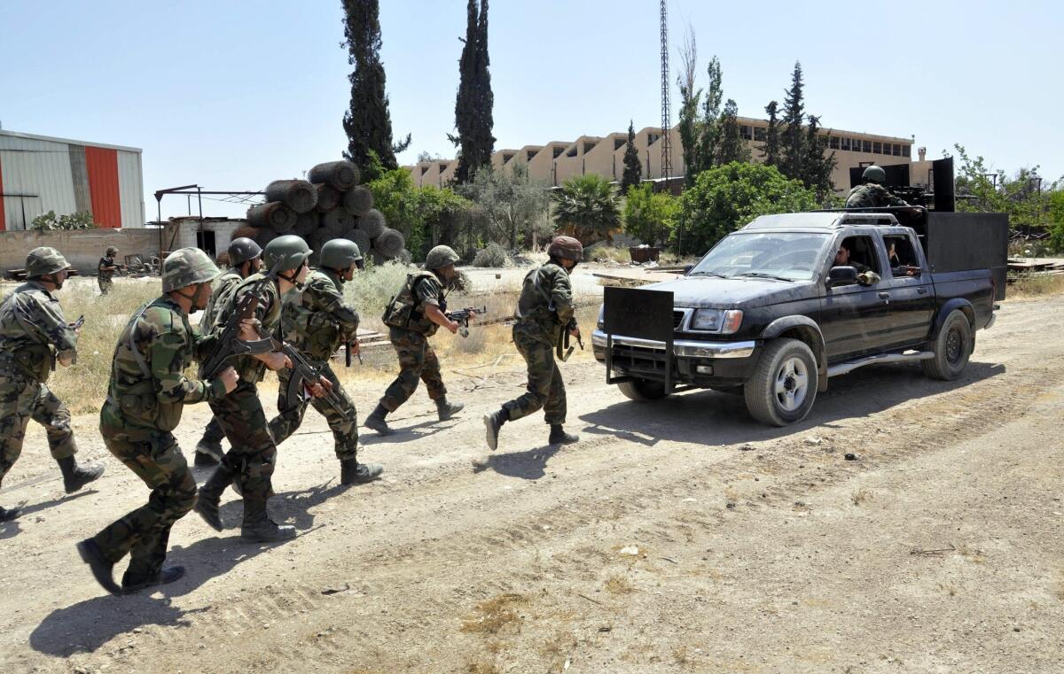 An image made available by the official Syrian Arab News Agency shows government soldiers taking up position during a May patrol in Duma, a suburb of Damascus.