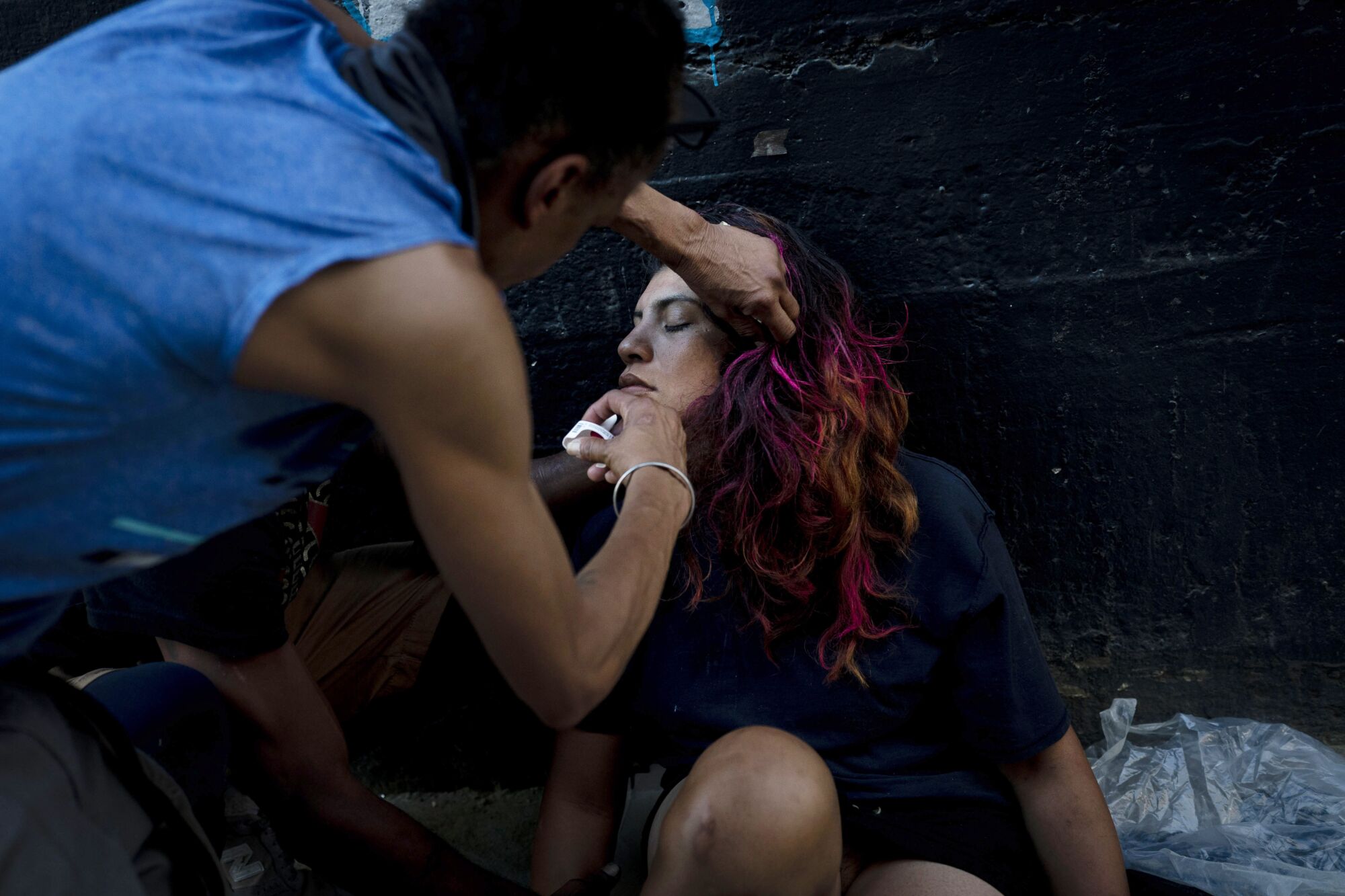 A homeless man injects Narcan nasal spray into the nose of a drug user in Los Angeles.