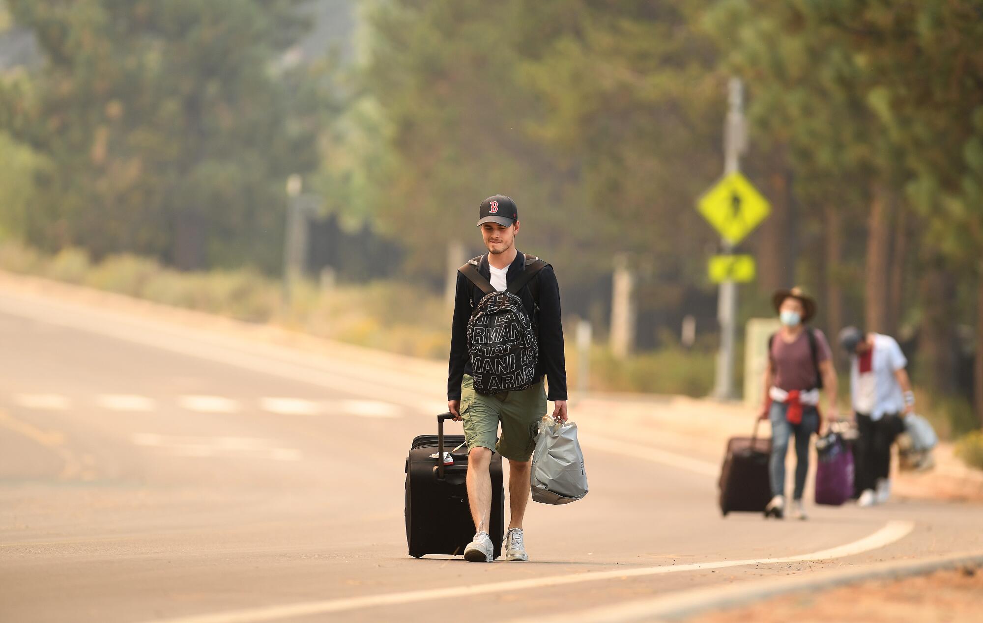 People carry luggage to evacuate ahead of the Caldor fire.