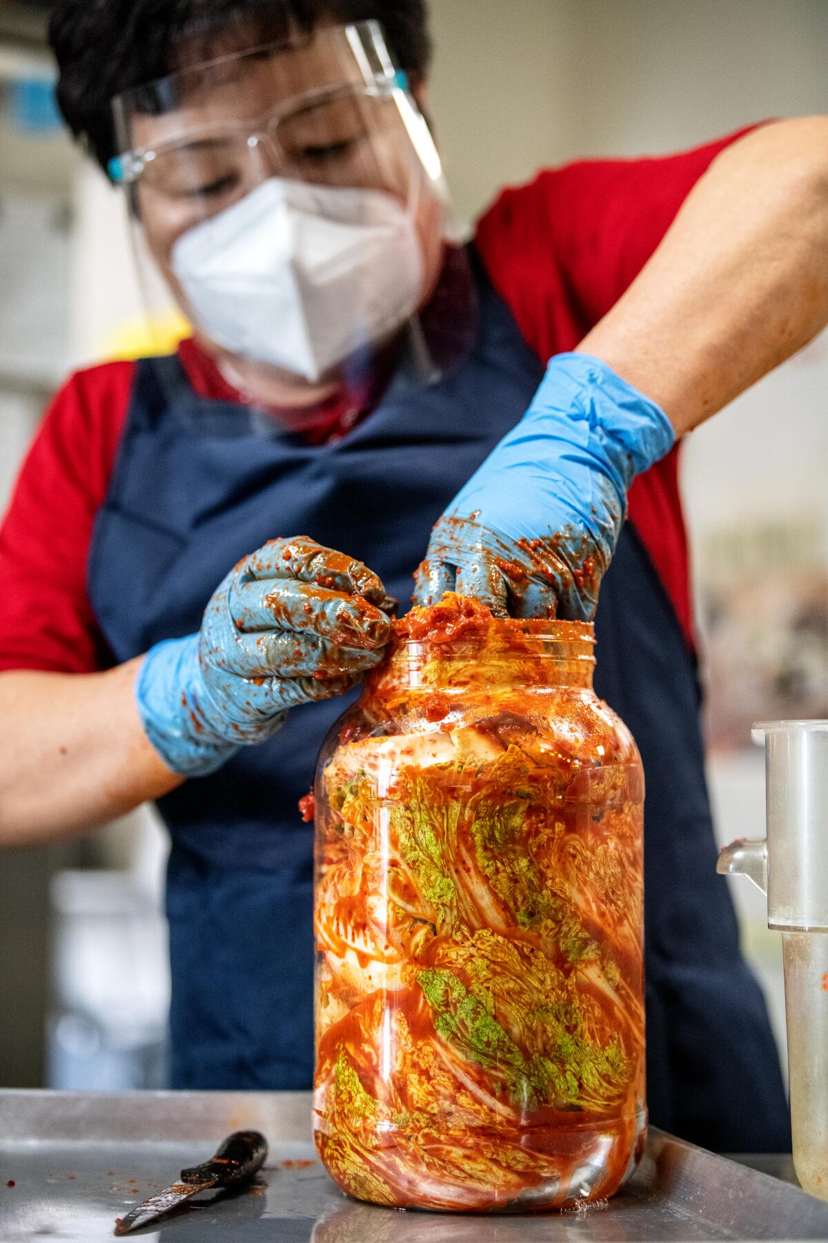 Kimchi Plus owner Young Hi Kim stuffs a jar with kimchi.