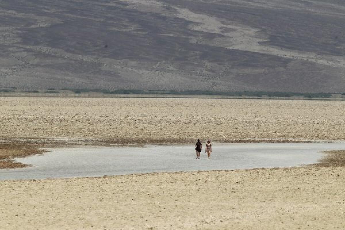 In Death Valley, visitors walk on the salt flat on Sunday at Badwater Basin, the lowest point in the nation at 282 feet below sea level. The extreme heat is drawing tourists to the national park.