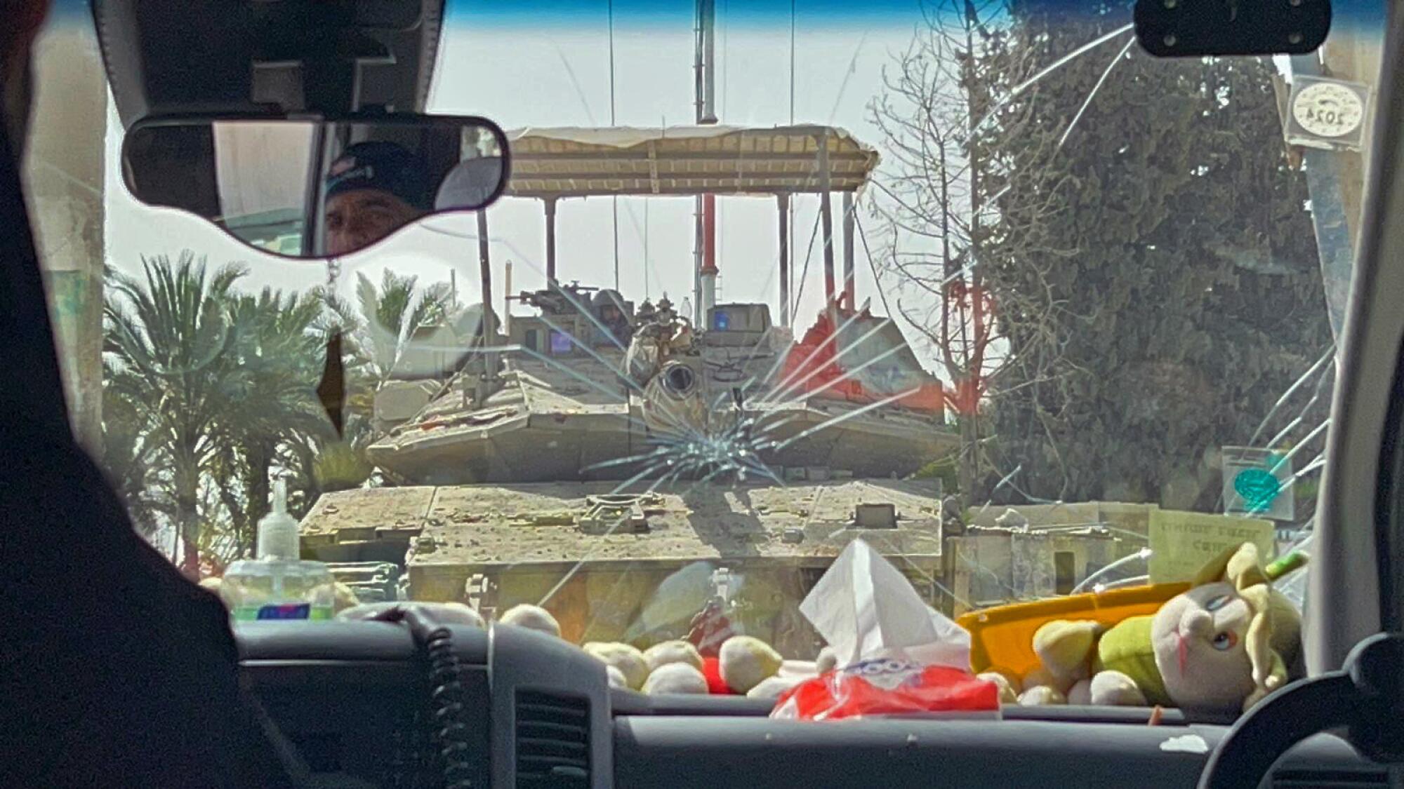 A tank is seen through the window of  a passenger vehicle.