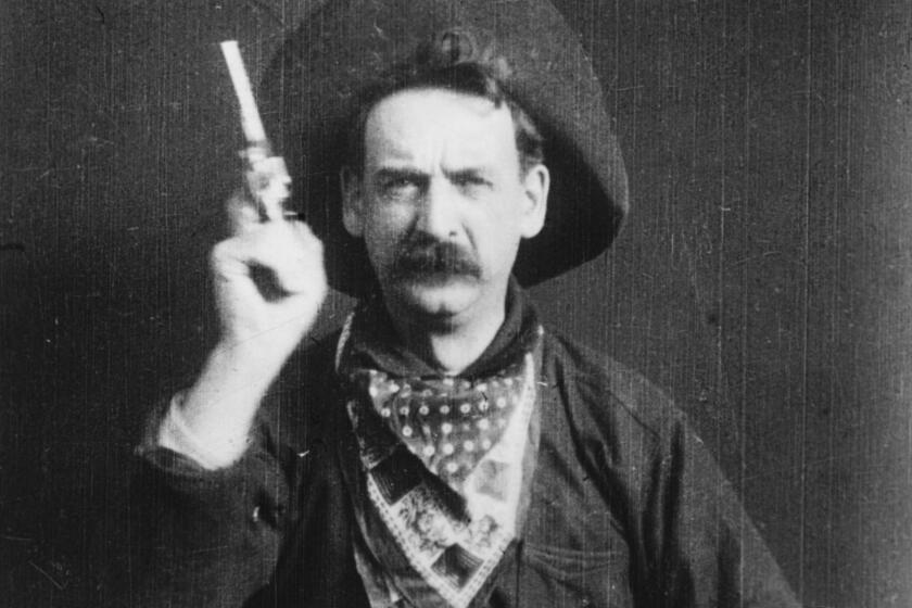 A bandit, played by George Barnes, prepares to shoot his gun at the camera in a scene