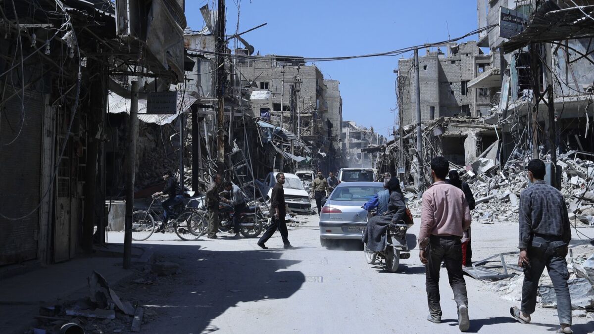 People walk among damaged buildings in the town of Duma, the site of a suspected chemical weapons attack, near Damascus, Syria, on April 16.