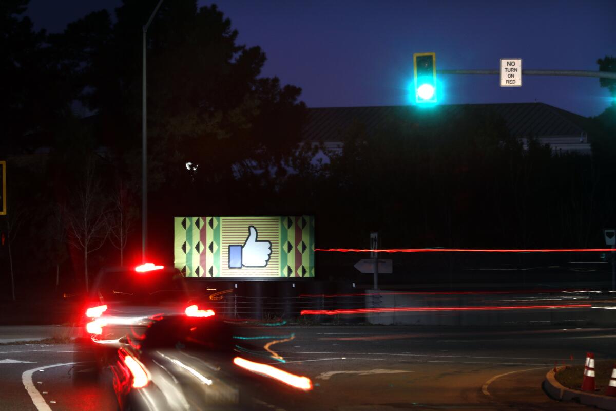 Cars pass a Facebook sign in East Palo Alto in 2021.