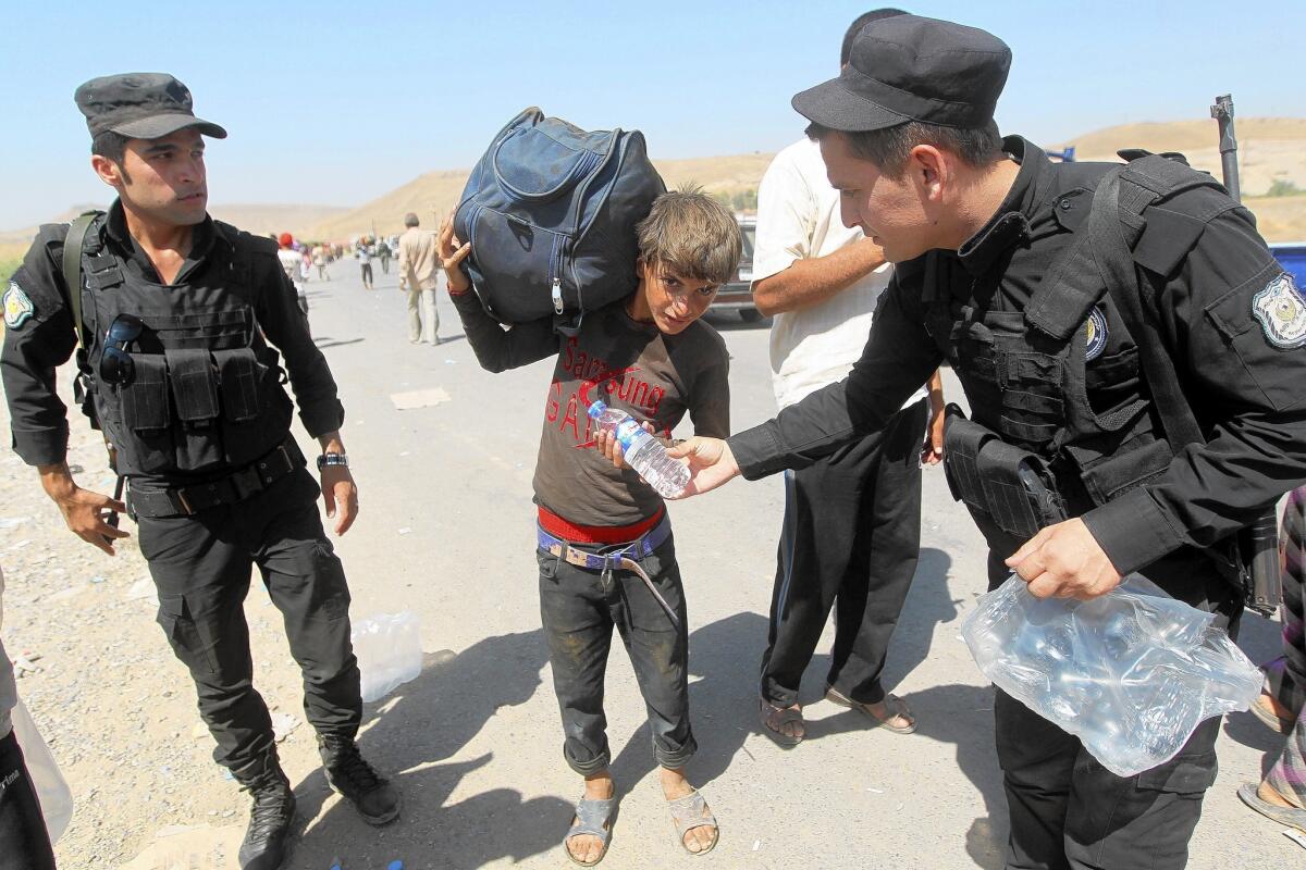 Members of the Kurdish forces, or peshmerga, hand out water to displaced Iraqis in northern Iraq.