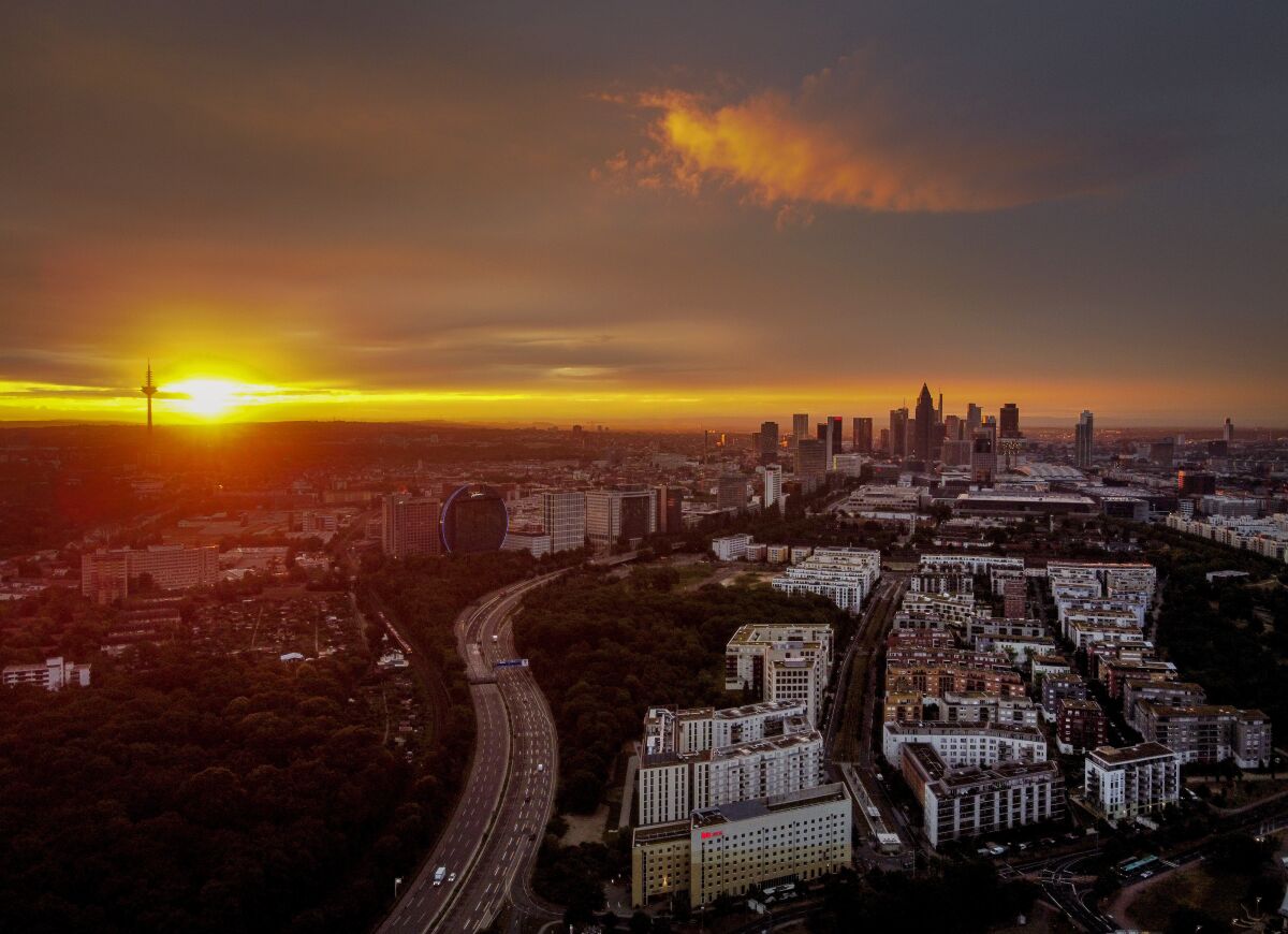 The sun rises over Frankfurt, Germany, with the buildings of the banking district at right, early Thursday, July 2, 2020. (AP Photo/Michael Probst)