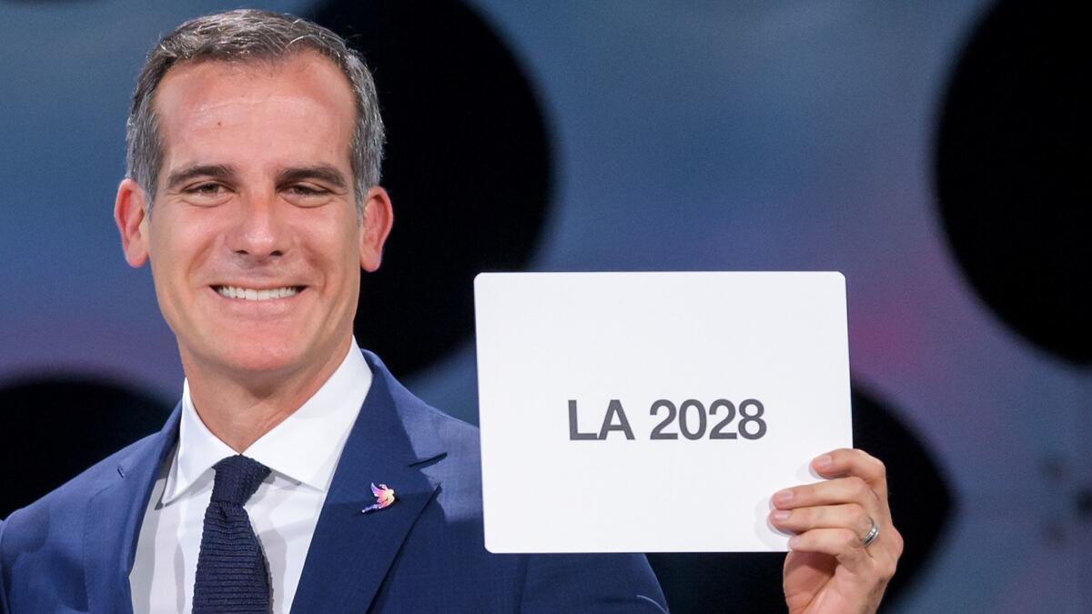 L.A. mayor Eric Garcetti holds a card bearing the name of LA 2028 after the vote by the International Olympic Committee to award the games to the city.