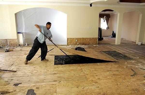 Raul Meza, a member of a private clean-up crew, removes a floor board in a water-damaged residence in the 13000 block of Venture Boulevard Avenue in Studio City three days after a water main broke on the corner of Dickens Street and Coldwater Canyon Avenue.