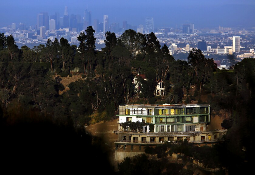 An unfinished mansion sits on a hillside.