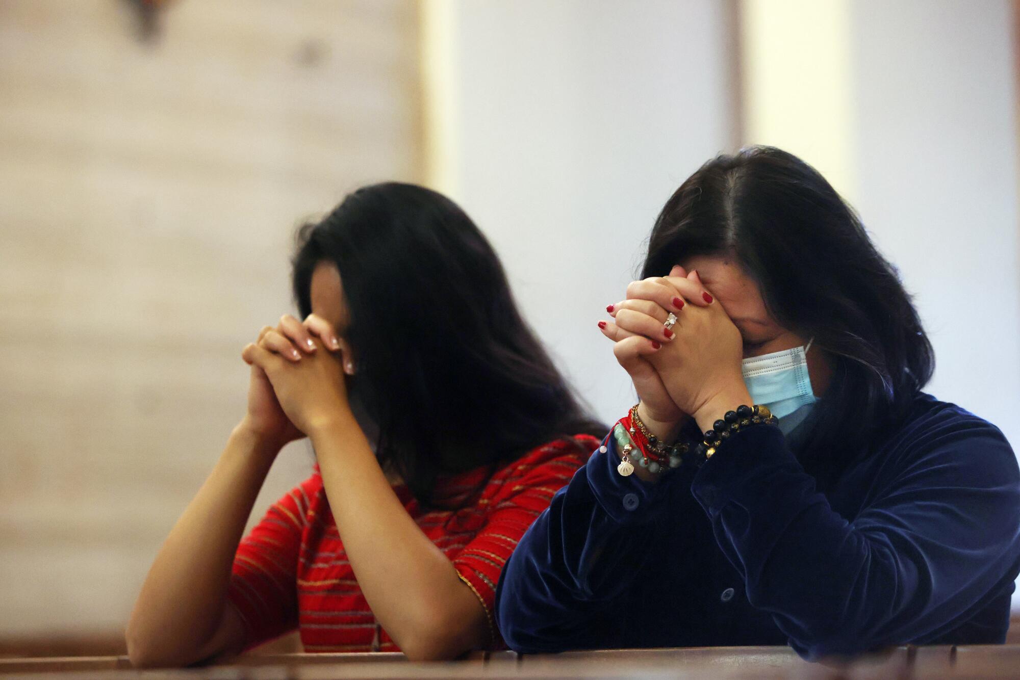 Elisha Soronio, left, and her mother, Mylenne Soronio pray during a Memorial Day Mass.