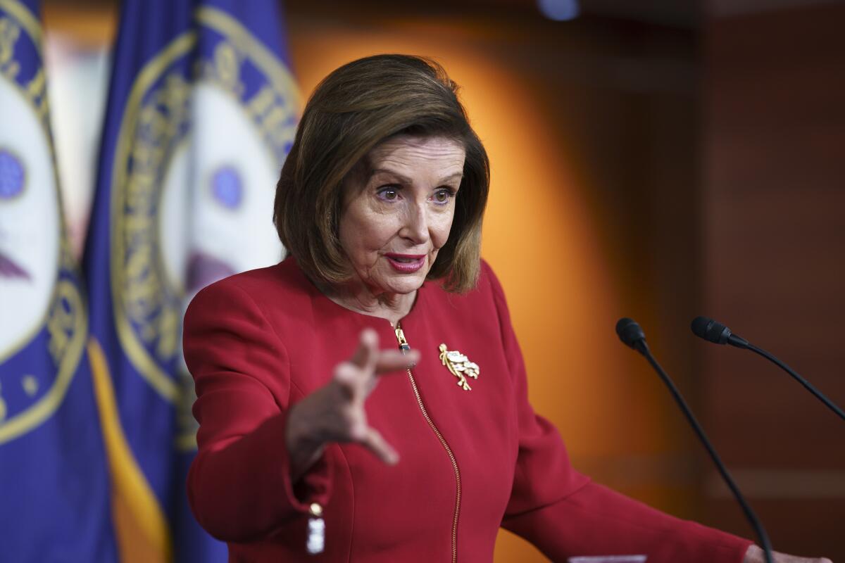 Speaker of the House Nancy Pelosi gestures while discussing President Biden's domestic agenda from behind a podium