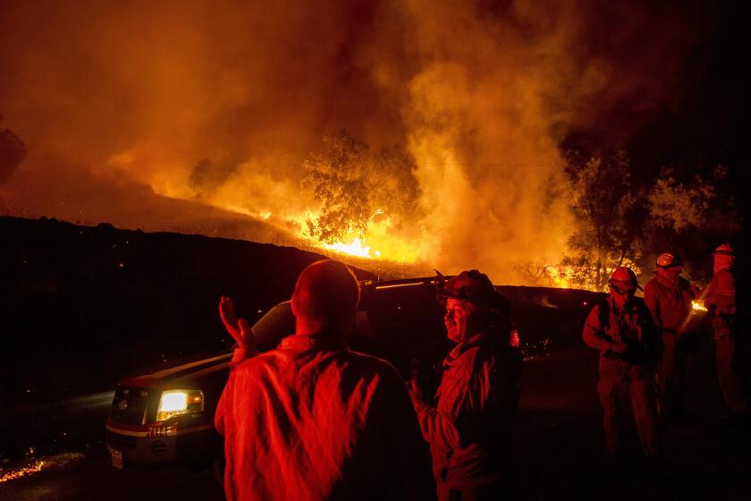 Firefighters confer while battling the Kincade Fire near Geyserville, Calif., on Thursday, Oct. 24, 2019. Portions of Northern California remain in the dark after Pacific Gas & Electric Co. cut power to prevent wildfires from sparking during dry and windy conditions. (AP Photo/Noah Berger)