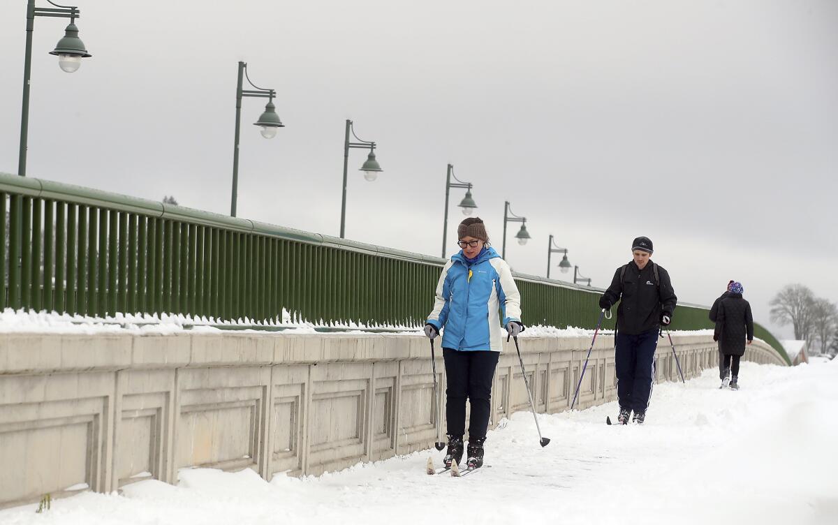 FILE - Erin Jaske and Scott Sandridge cross country ski across the Manette bridge in Bremerton, Wash., on a snowy day, in this Saturday, Feb. 13, 2021, file photo. During the pandemic, people around the world sought relief from lock downs and working from home in leisure sports. (Meegan M. Reid/Kitsap Sun via AP, File)/Kitsap Sun via AP