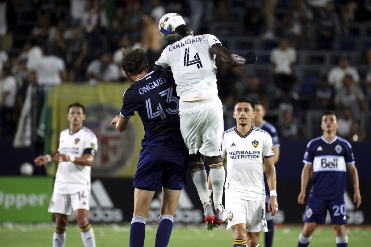 Los Angeles Galaxy defender Séga Coulibaly (4) heads the ball against Vancouver Whitecaps midfielder Easton Ongaro (43) during the first half of an MLS soccer match Saturday, Aug. 13, 2022, in Carson, Calif. (AP Photo/Raul Romero Jr.)