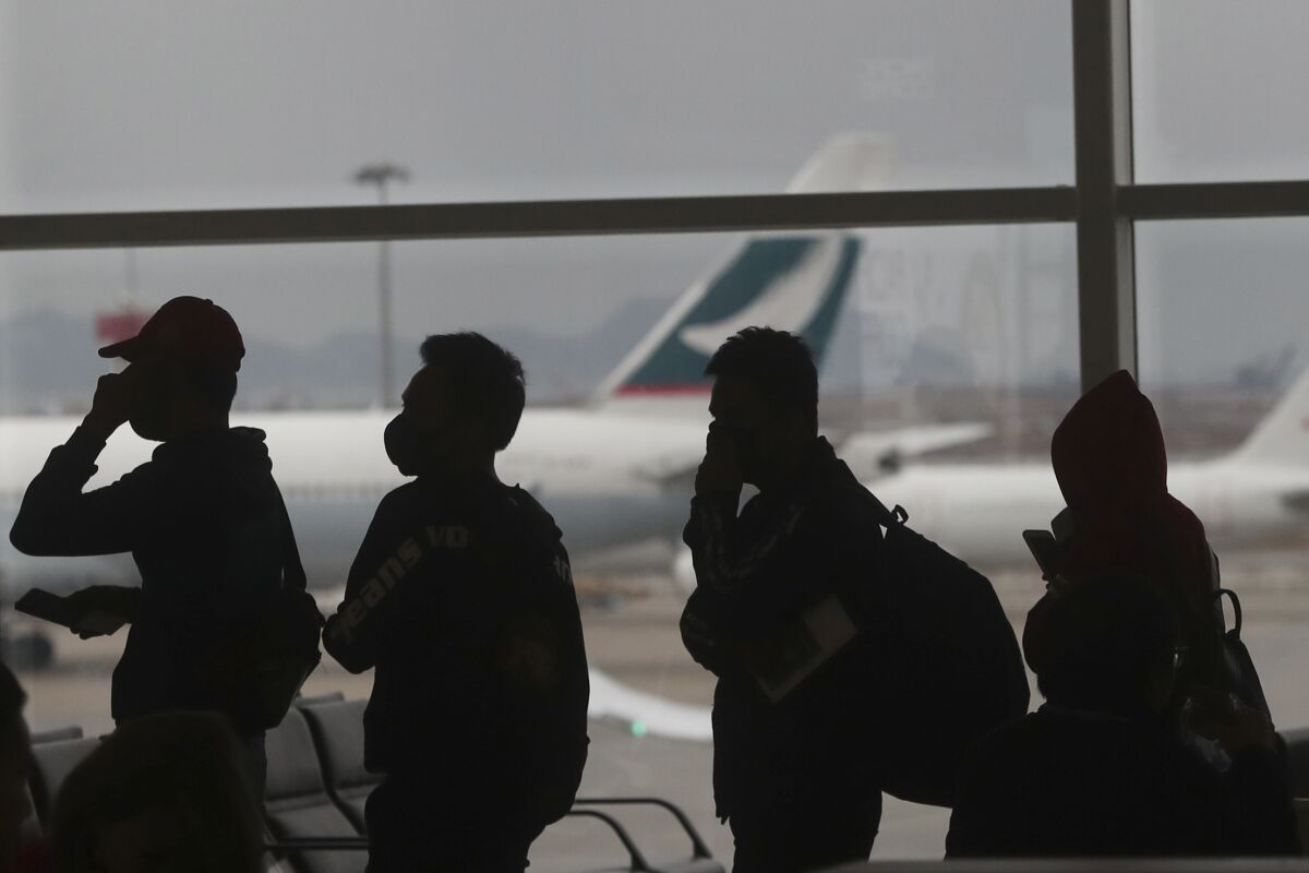 People wearing masks line up for departure at Hong Kong airport in Hong Kong, Tuesday, Feb. 4, 2020. Hong Kong on Tuesday reported its first death from a new virus, a man who had traveled from the mainland city of Wuhan that has been the epicenter of the outbreak. (AP Photo/Achmad Ibrahim)