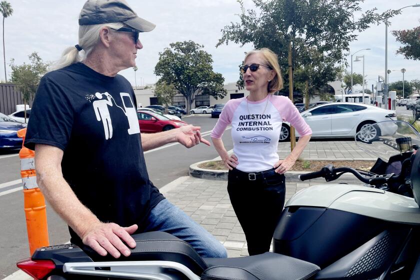 Paul Scott, co-founder of Plug-In America, chats with his ex-wife Zan Dubin-Scott at a Tesla charging station, 14th and Santa Monica Blvd. Paul owns a Tesla but rents it out. His daily vehicle is an electric Zero motorcycle. Zan drives a Chevy Volt.