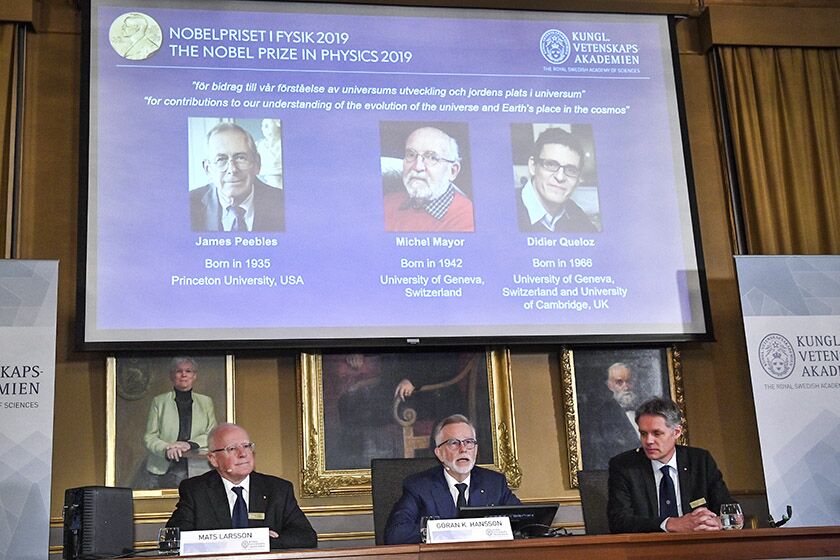 The winners of the Nobel Prize in Physics are projected on a screen during news conference in Stockholm on Tuesday. They are, from left on screen, James Peebles, Michel Mayor and Didier Queloz.