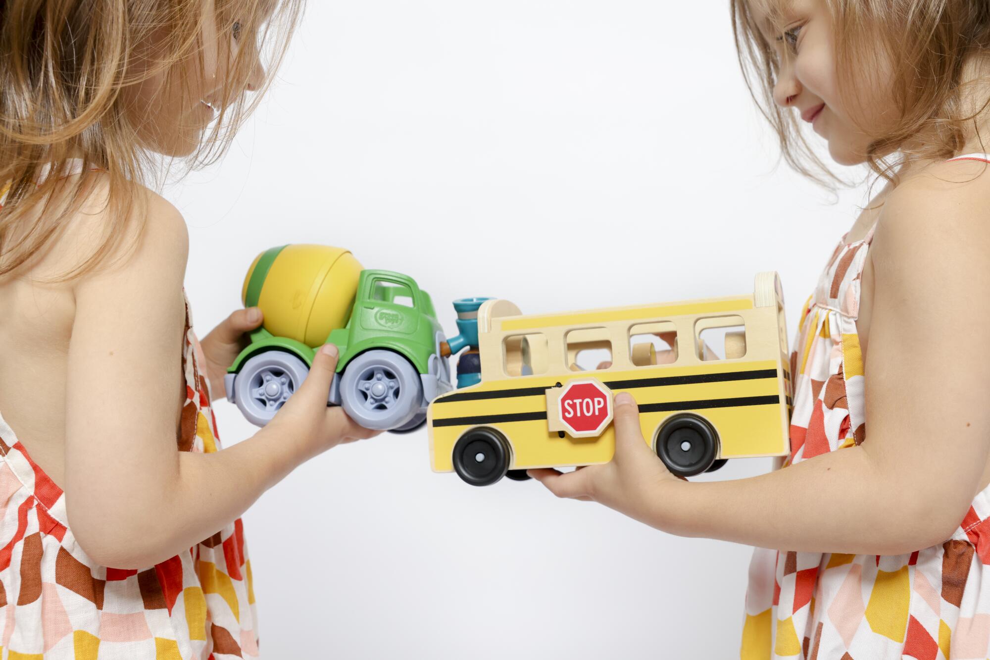 Penny and River Atchison, left and right, 4, play with a plastic and wood car at their home.