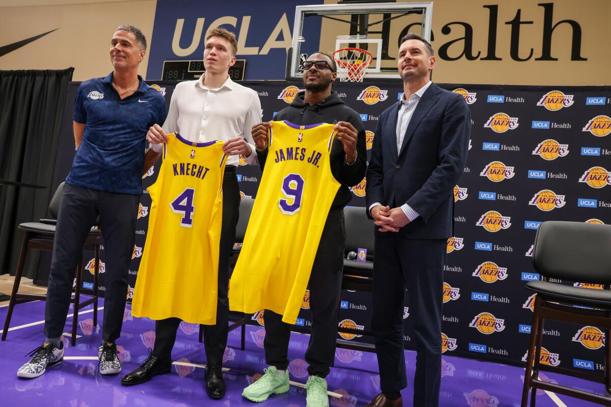 Dalton Knecht and Bronny James, with jerseys in hand, are introduced by GM Rob Pelinka, left, and coach JJ Redick, right.