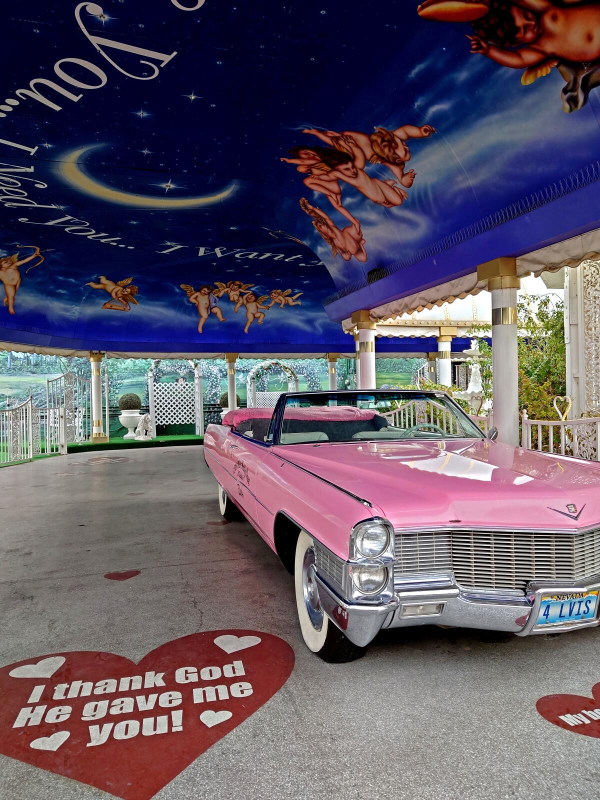 A pink Cadillac convertible sits parked in a drive-through wedding tunnel