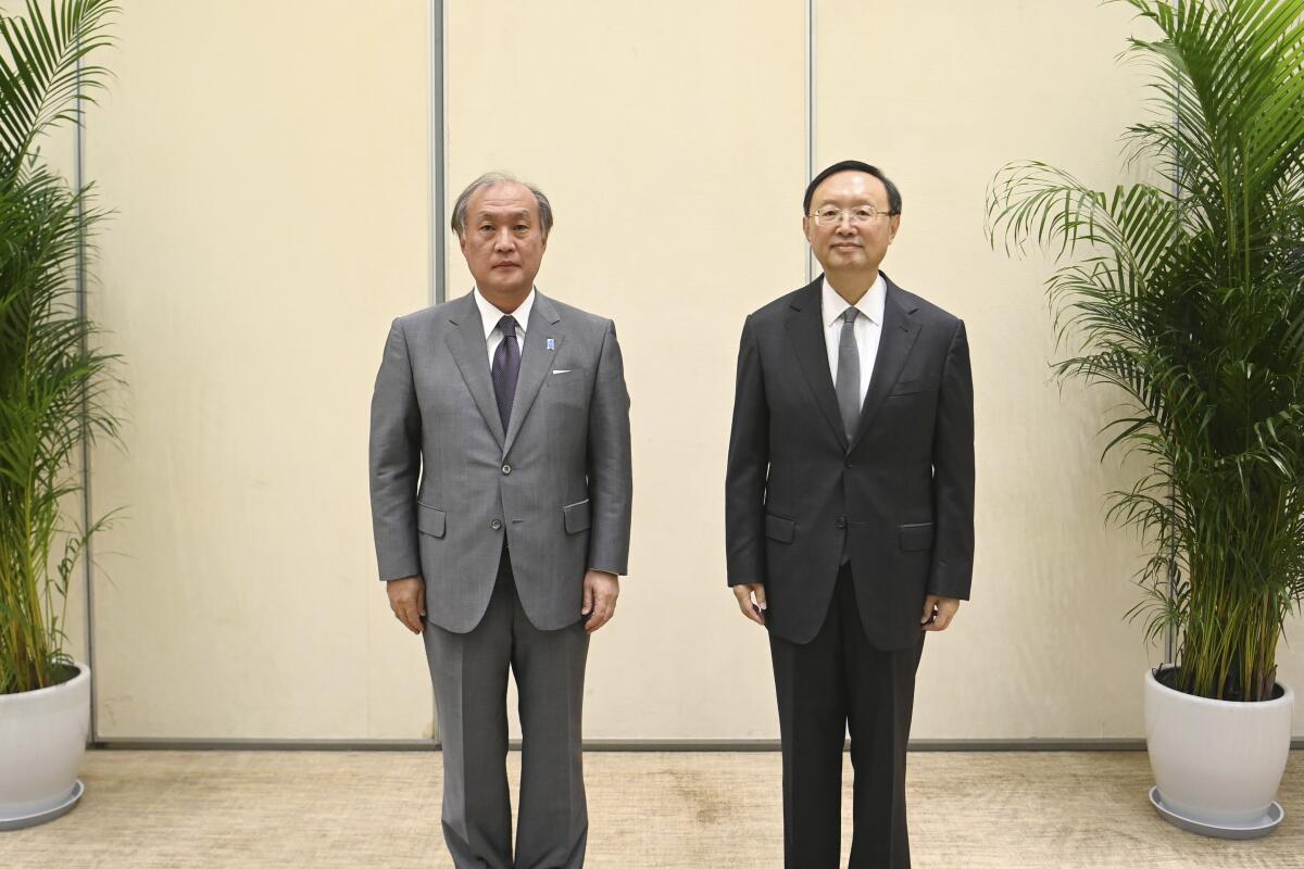 In this photo released by Xinhua News Agency, Yang Jiechi, right, a member of the Political Bureau of the Communist Party of China (CPC) Central Committee and director of the Office of the Foreign Affairs Commission of the CPC Central Committee, poses for photos with Akiba Takeo, head of Japan's National Security Secretariat, during the ninth China-Japan high-level political dialogue in Tianjin municipality in northern China Wednesday, Aug. 17, 2022. Chinese and Japanese officials have met in northern China amid renewed tensions over China's military threats against Taiwan that have prompted protests from Tokyo over the firing of Chinese missiles into Japan's exclusive economic zone. (Zhao Zishuo/Xinhua via AP)