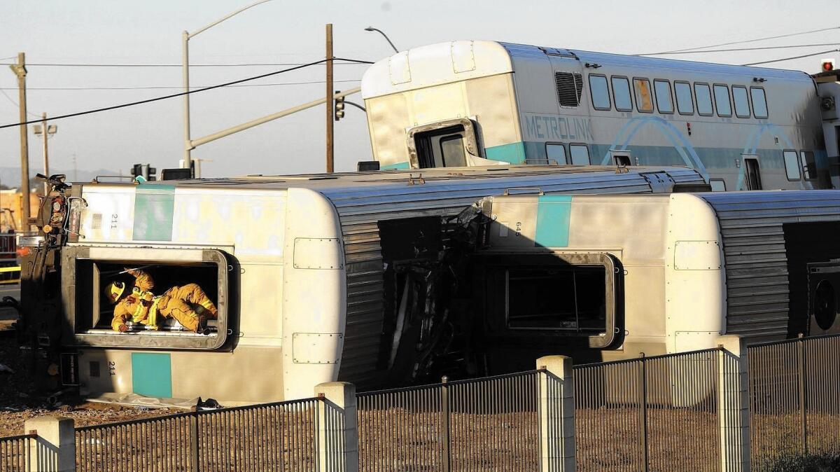 A firefighter climbs out of an overturned Metrolink train car that derailed in Oxnard on Feb. 24.