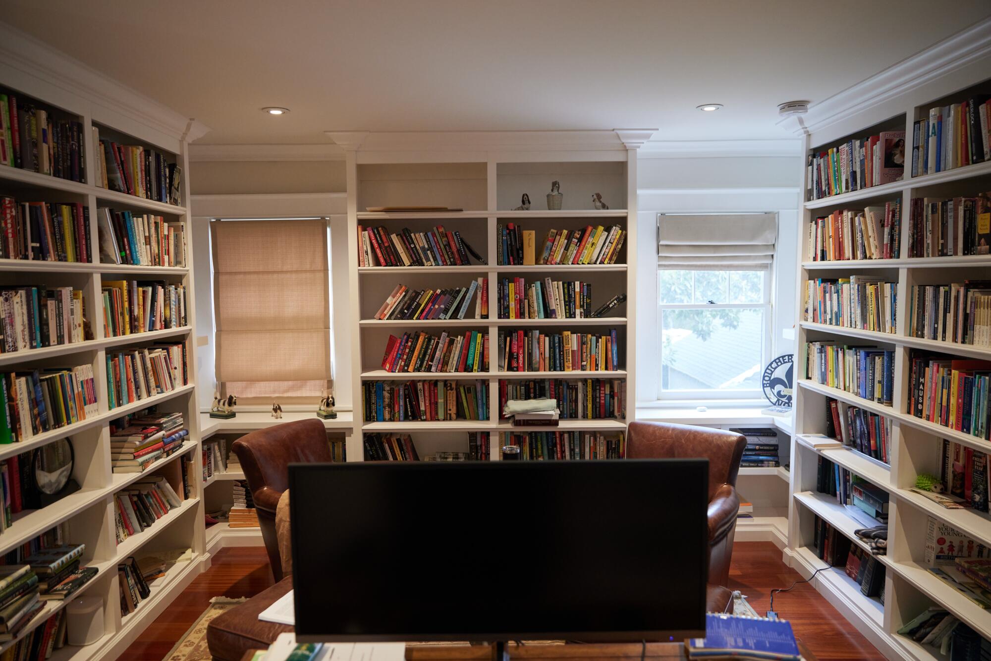 A photo of a room, where three of the walls are covered in bookshelves.