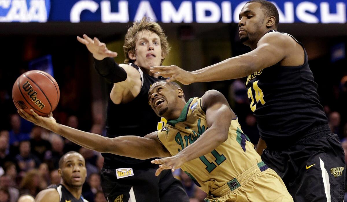 Notre Dame guard Demetrius Jackson attempts a layup against the defense of Wichita State guard Evan Wessel, left, and forward Shaquille Morris (24) during the second half of the Irish's 81-70 victory in a Midwest Regional semifinal Thursday night.