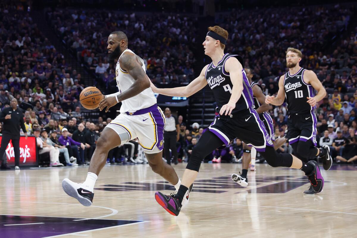 Lakers star LeBron James drives to the basket in front of Sacramento Kings guard Kevin Huerter.
