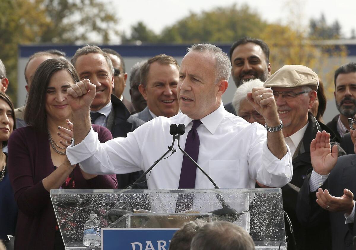 Darrell Steinberg stands at a podium amid an applauding crowd.
