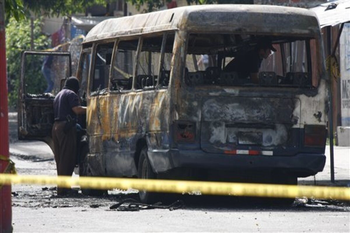A police officer inspects a burnt bus in San Salvador, Monday, June 21, 2010. The bus was attacked Sunday night while driving along its regular route in the northern area of San Salvador, killing at least 10 people who were aboard and leaving several others badly hurt. (AP Photo/Luis Romero)