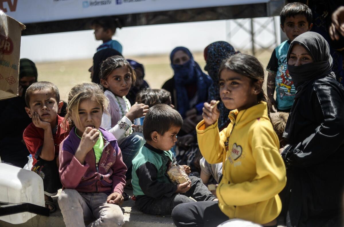 Syrian refugees sit on the side of a road that leads to the Akcakale border gate as they wait to return to their home in the northern Syrian town of Tel Abyad, in Sanliurfa province. About half of the world's record 60 million displaced persons are children, the UNHCR said in a new report on the humanitarian crisis.