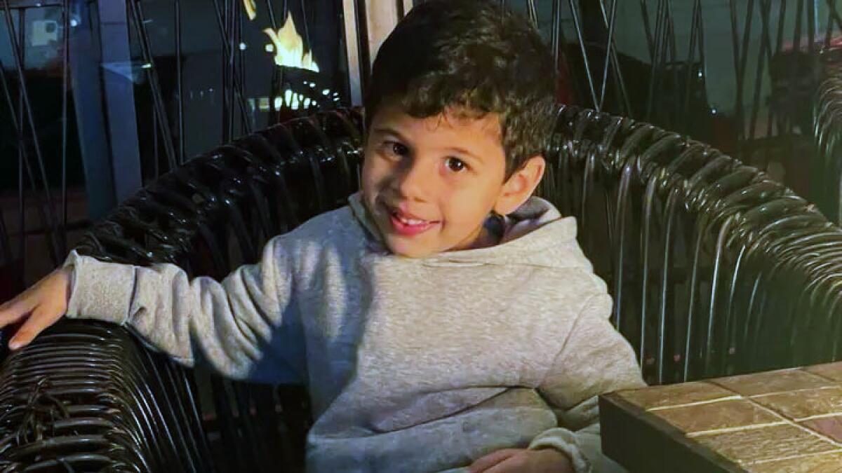 A young boy smiles at the camera while siting in a chair