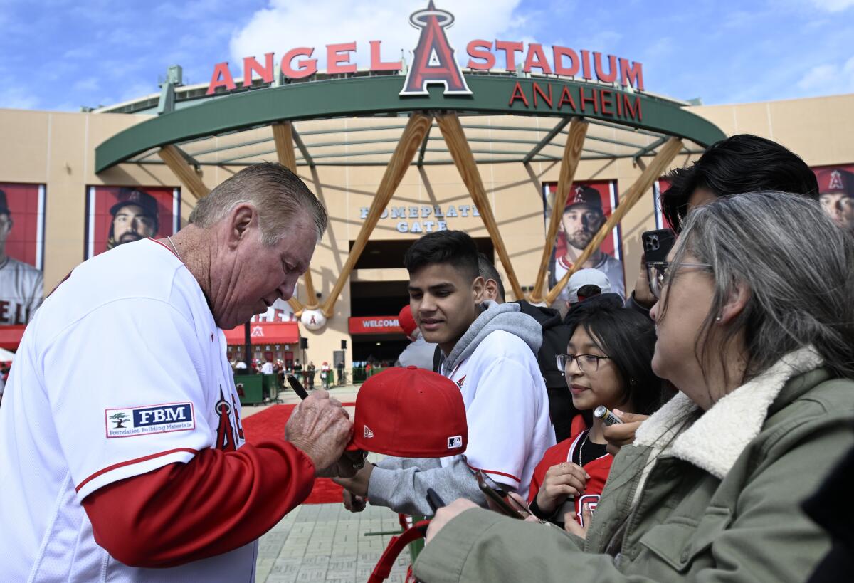 Mickey Hatcher, ancien entraîneur des frappeurs des Angels et joueur des Dodgers, signe des autographes pour un fan avant le match de vendredi.