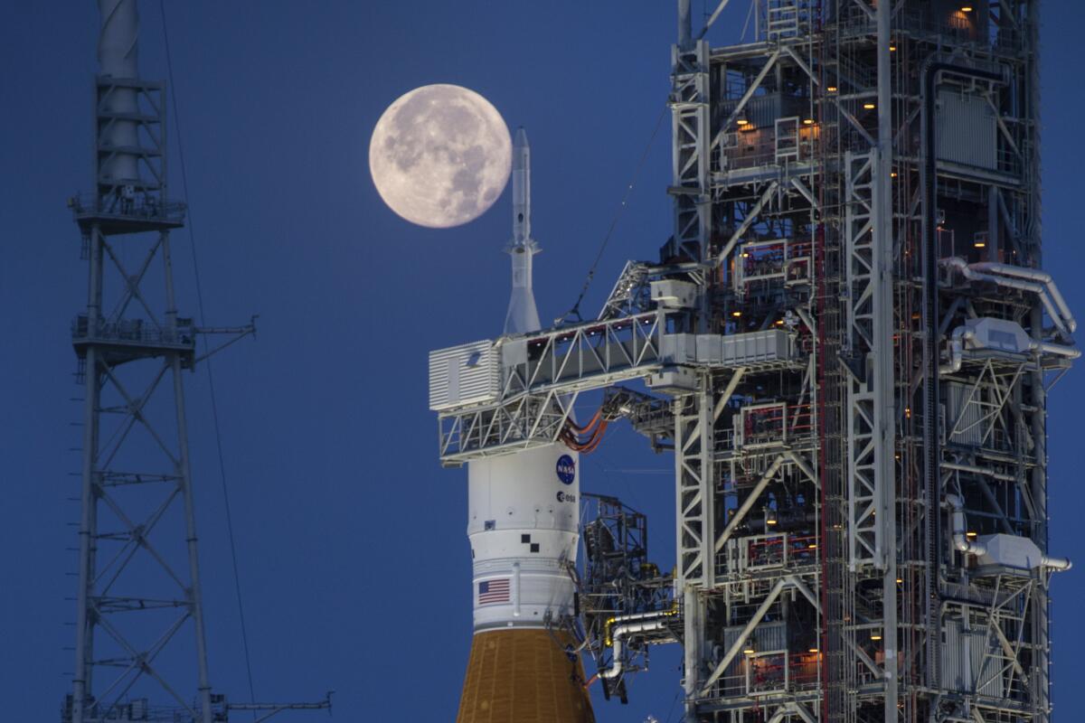 A full moon is seen behind a launch pad