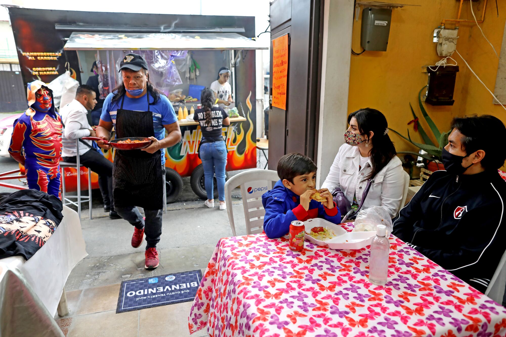 Wrestler José Gutiérrez Hernández, 48, center, serves food truck customers in Mexico City's El Risco CTM neighborhood.