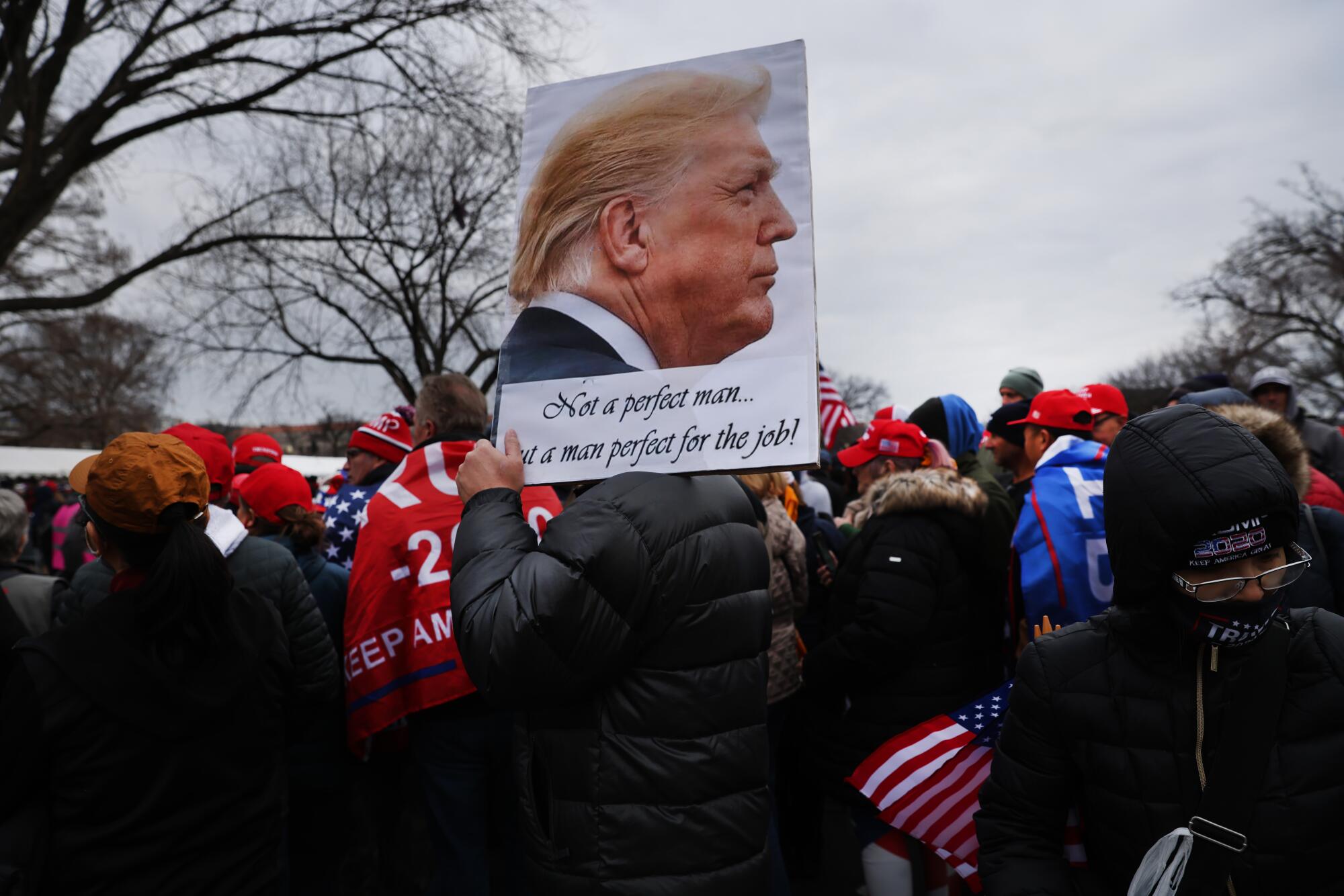 A Trump supporter carries a picture of him reading "Not a perfect man, but a man perfect for the job."