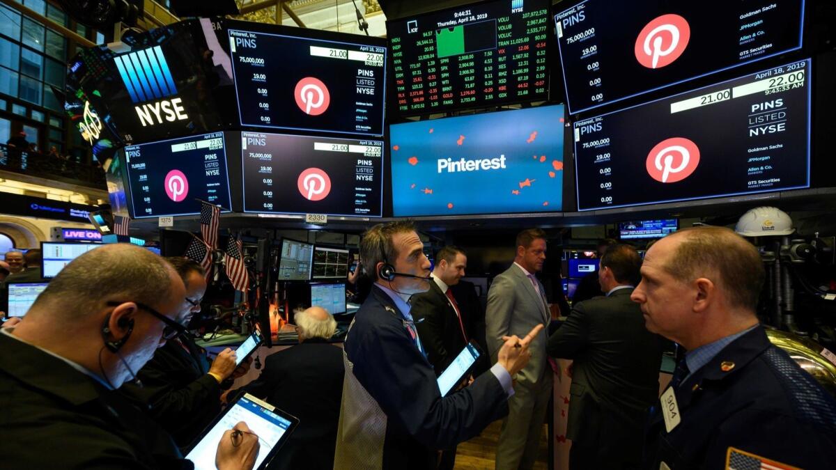 Traders work Thursday at the New York Stock Exchange, where the Pinterest logo is displayed on screens.