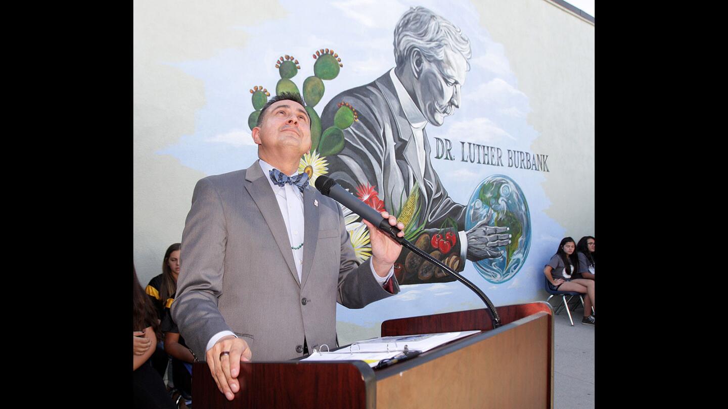 Luther Burbank Middle School Principal Dr. Oscar Macias takes the podium to close the ceremony as a jet, taking off from the Bob Hope Airport, flys overhead at the Mural Dedication and Ribbon-Cutting Ceremony at the middle school on Tuesday, March 15, 2016. The mural depicts Dr. Luther Burbank and features about his life.