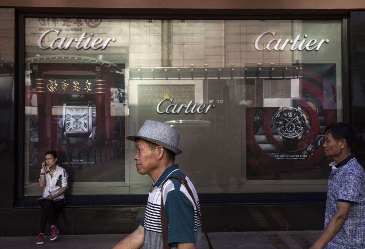 Chinese shoppers walk past a luxury store in an upscale shopping district in Beijing.