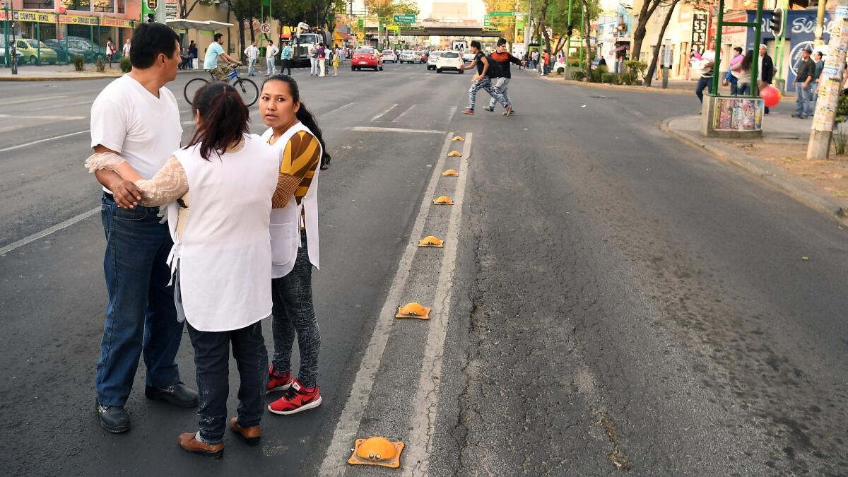 People in Mexico City hold onto one another as the ground shakes during an earthquake.