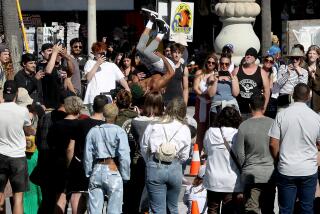 Los Angeles, CA - April 06: The highly contagious norovirus, sometimes referred to as the stomach flu, is on the rise in California, prompting state health officials to urge healthcare providers to step up disinfection efforts in a bid to check the spread. Above, visitors to Venice Beach watch a performer on Thursday, April 6, 2023. (Luis Sinco / Los Angeles Times)