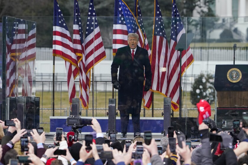 President Trump speaks onstage at a rally Wednesday behind bulletproof glass flanked by U.S. flags in front of supporters.