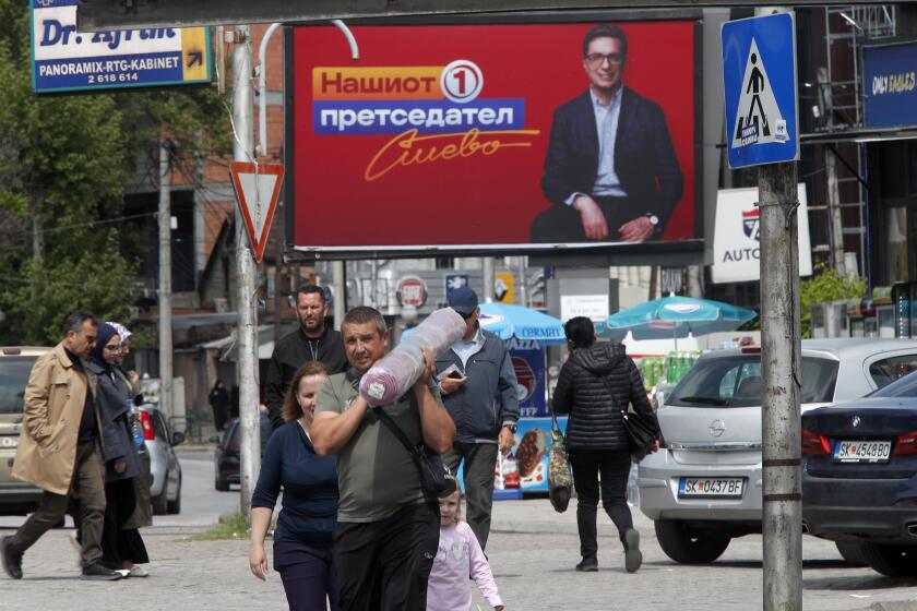 People walk past election poster of Stevo Pendarovski, incumbent President and a presidential candidate backed by the ruling social democrats (SDSM), in a street in Skopje, North Macedonia, on Monday April 22, 2024. Voters go to the polls in North Macedonia on Wednesday April 24 for the first round of presidential elections, the seventh such election since the Balkan country gained independence from the former Yugoslavia in 1991, where seven candidates are vying for the largely ceremonial position. (AP Photo/Boris Grdanoski)