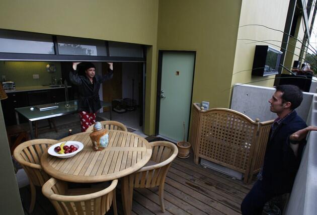 Resident Luca Forcellini, left, chats with Weibrecht on the terrace of his apartment, where roll-up glass separates the terrace from the indoor dining area and kitchen.