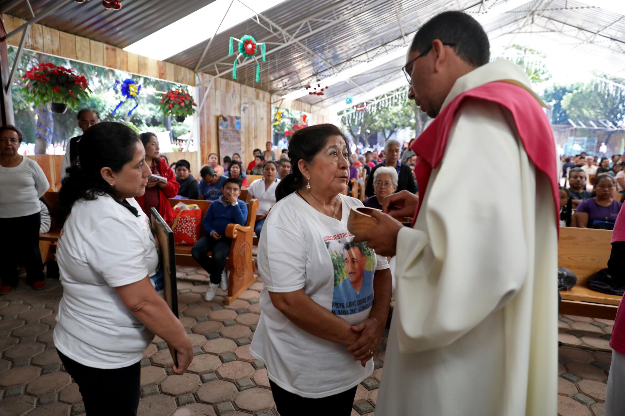 Maricela Pe?aloza Flores, center, with daughter Georgina Quiroz Pe?aloza, asks the priest if she can make an announcement about her husband in Tepoztlán, Mexico, on Dec. 15.