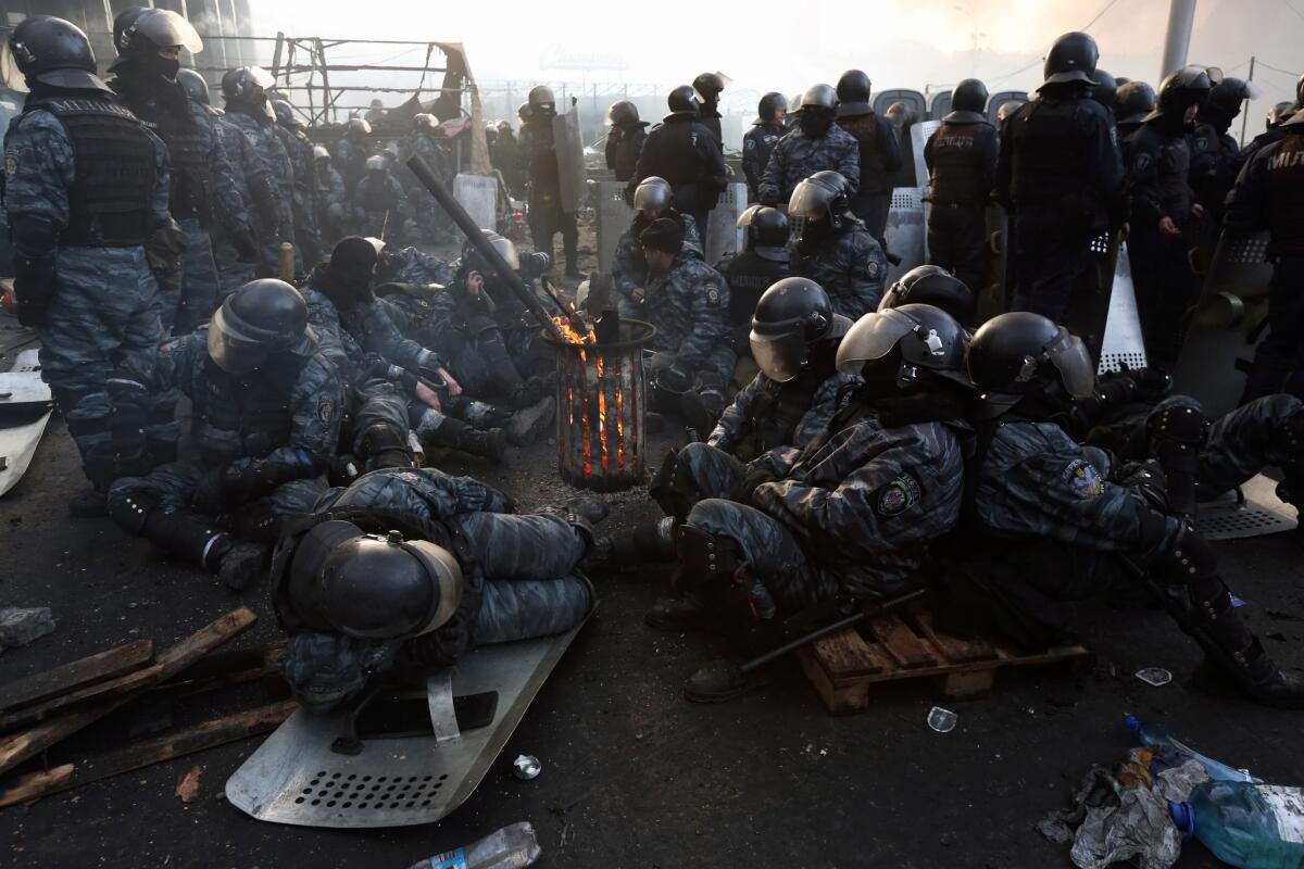 Riot police take a break near Kiev's Independence Square Wednesday afternoon after two days of clashes with the opposition.
